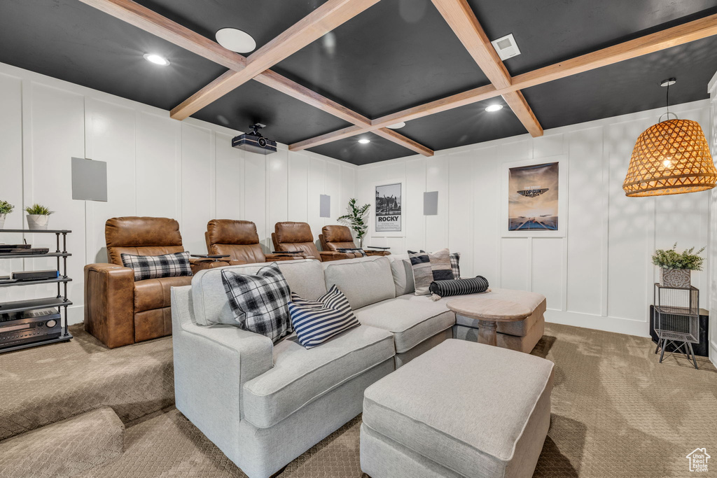Carpeted cinema room with coffered ceiling and beam ceiling