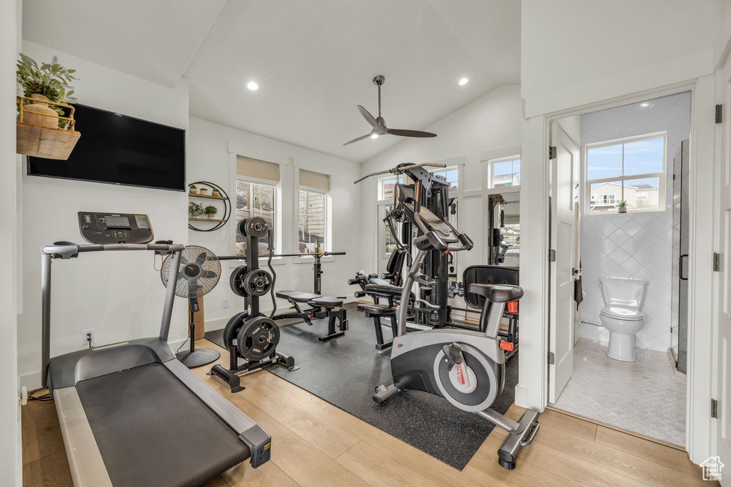 Exercise room with lofted ceiling, ceiling fan, and light hardwood / wood-style flooring