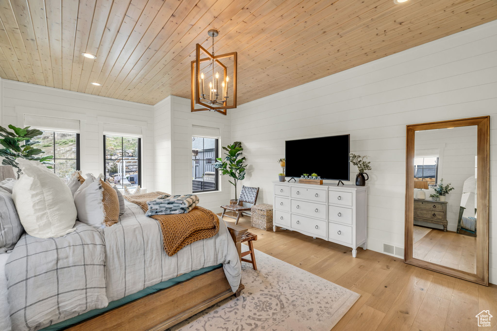 Bedroom featuring light hardwood / wood-style floors, wooden ceiling, and a chandelier
