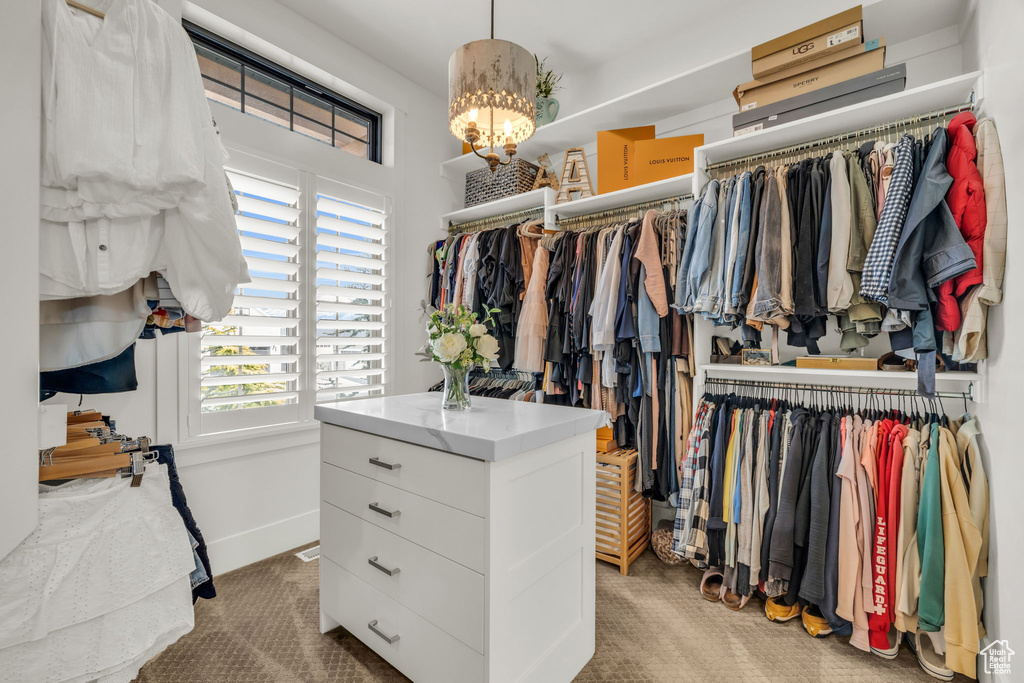 Walk in closet with light carpet and a notable chandelier