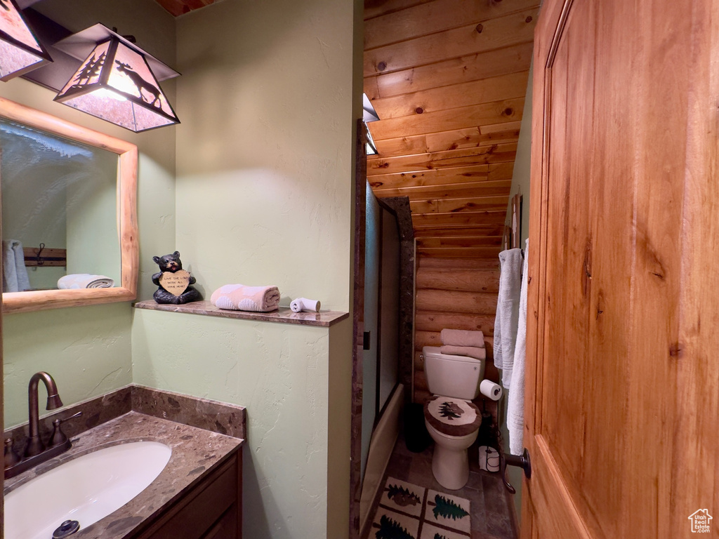 Full bathroom featuring vanity, toilet, combined bath / shower with glass door, and tile floors