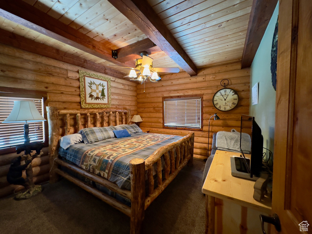 Bedroom featuring rustic walls, ceiling fan, beam ceiling, and dark colored carpet