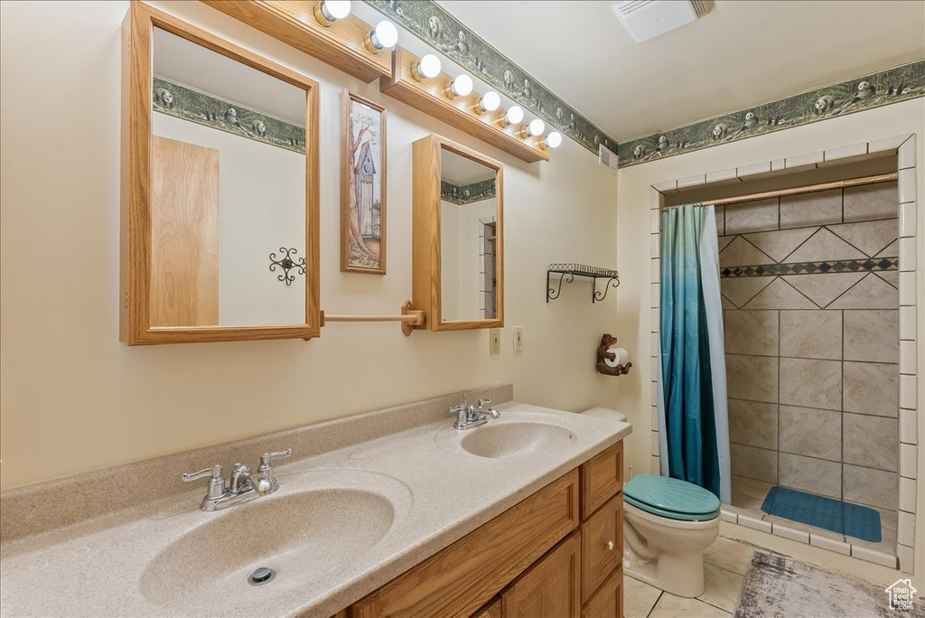 Bathroom featuring dual sinks, tile flooring, oversized vanity, toilet, and a shower with shower curtain