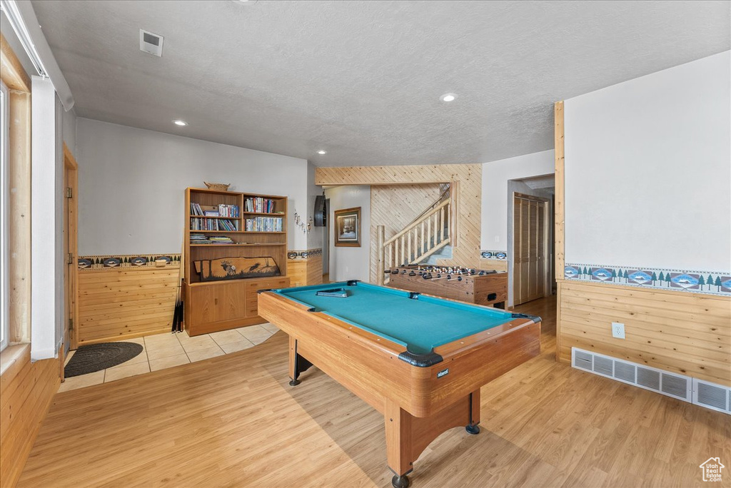 Recreation room with a textured ceiling, pool table, and light hardwood / wood-style flooring