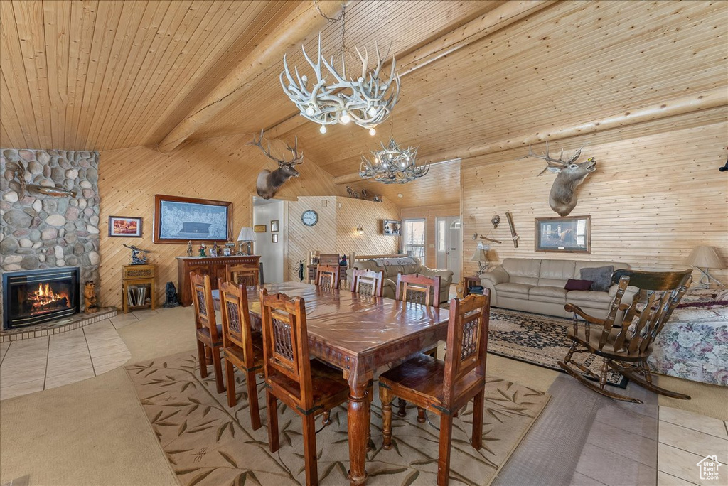 Dining area featuring a notable chandelier, a stone fireplace, wood ceiling, and beamed ceiling