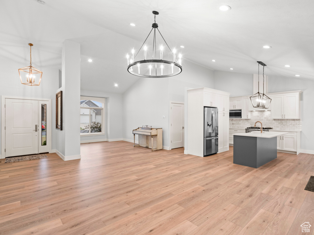Kitchen with light hardwood / wood-style floors, stainless steel appliances, and decorative light fixtures