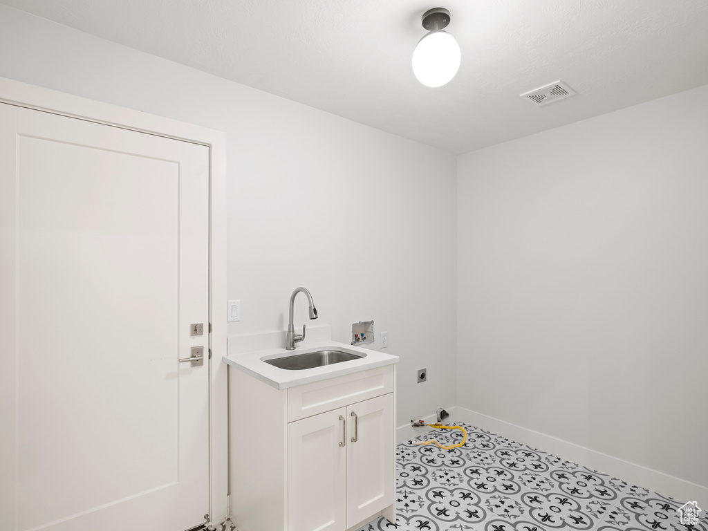 Laundry room featuring light tile flooring, hookup for an electric dryer, cabinets, hookup for a washing machine, and sink