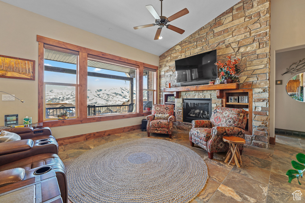 Living room with a stone fireplace, ceiling fan, tile flooring, and a wealth of natural light