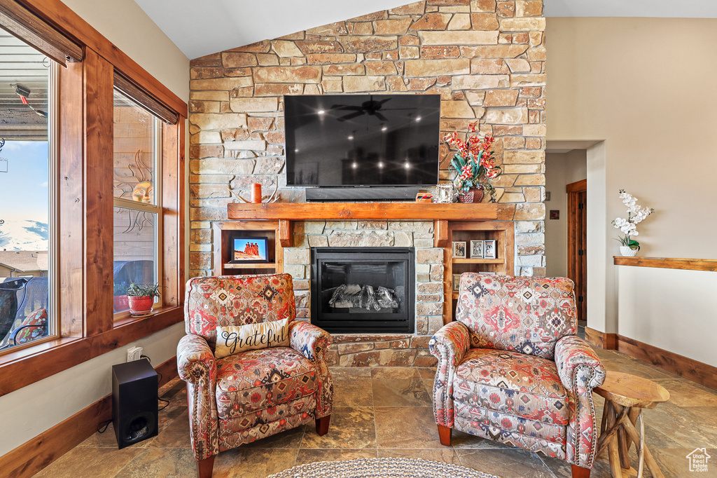 Living room with a stone fireplace, tile flooring, and vaulted ceiling