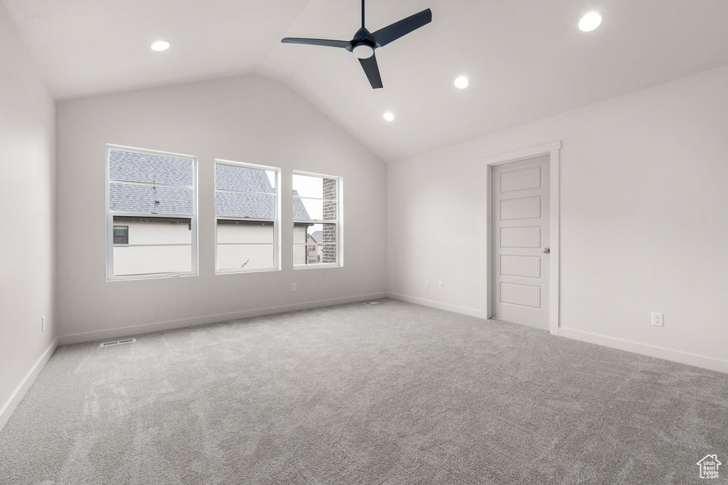 Empty room featuring light carpet, ceiling fan, and lofted ceiling