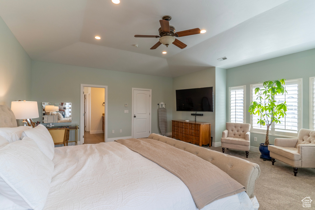 Bedroom with light carpet, vaulted ceiling, connected bathroom, and ceiling fan