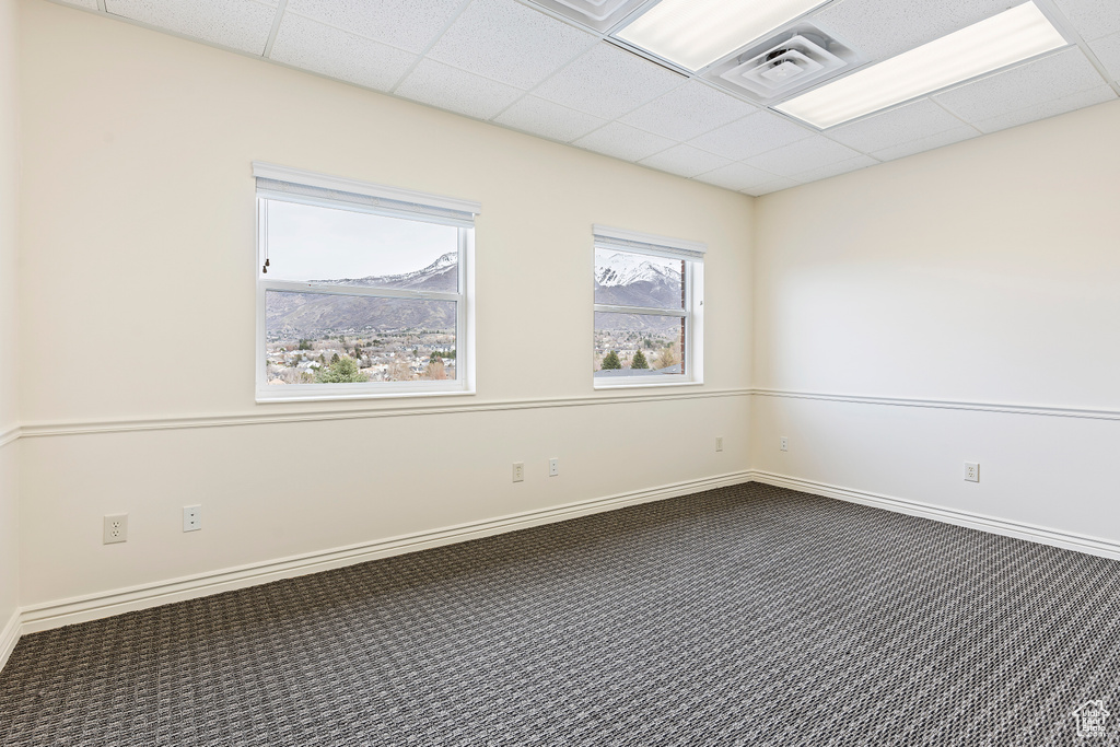 Carpeted empty room featuring a mountain view and a paneled ceiling