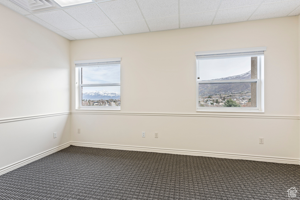 Spare room featuring a mountain view, a paneled ceiling, dark carpet, and plenty of natural light