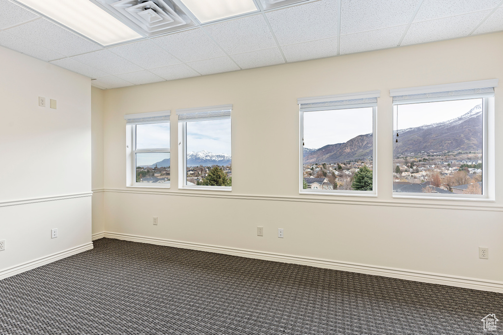 Unfurnished room with a paneled ceiling, a mountain view, and a healthy amount of sunlight