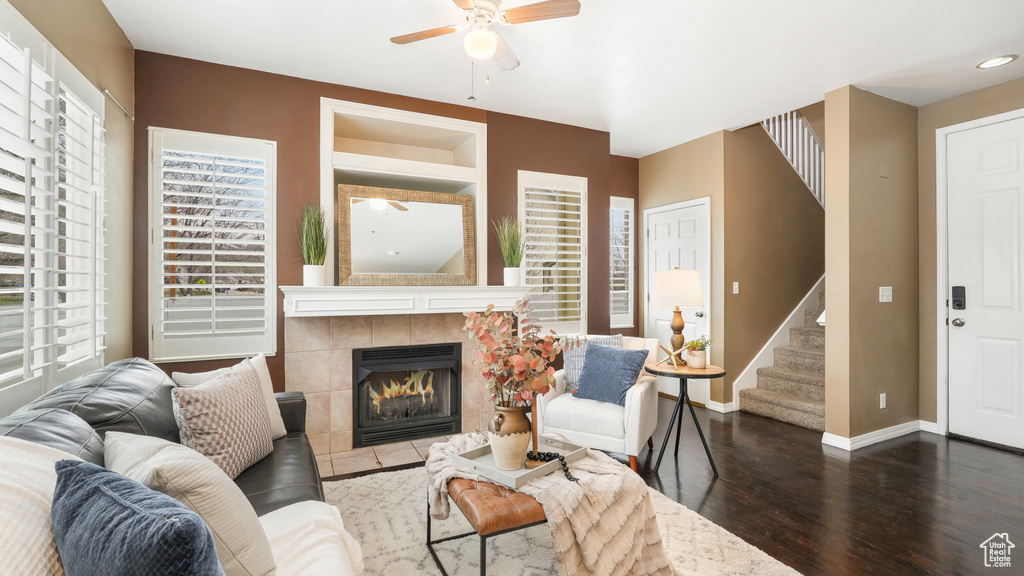 Living room featuring ceiling fan, a tiled fireplace, and dark hardwood / wood-style flooring