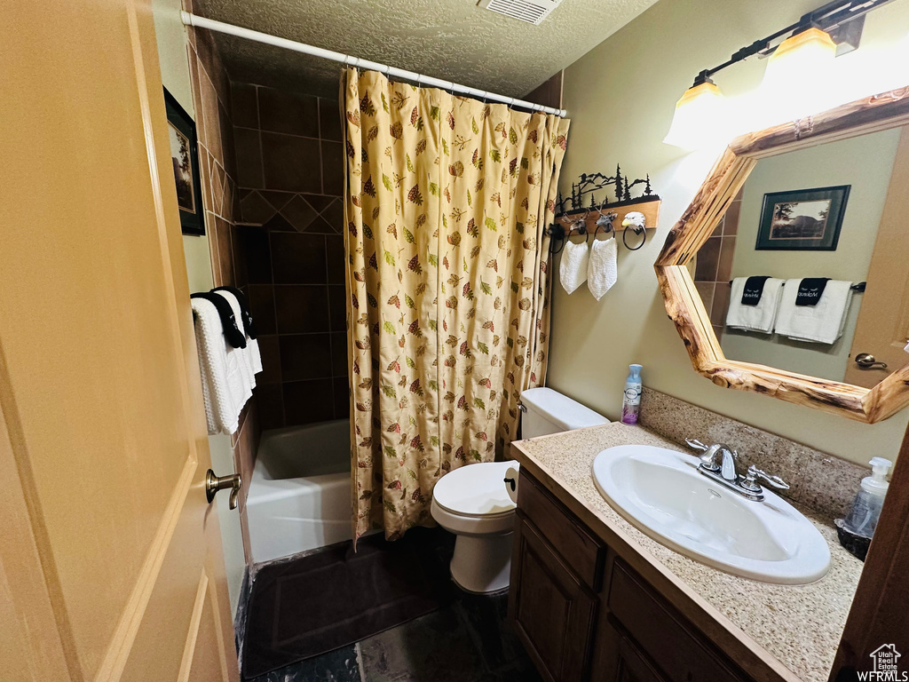 Full bathroom featuring toilet, a textured ceiling, vanity, shower / bath combination with curtain, and tile floors