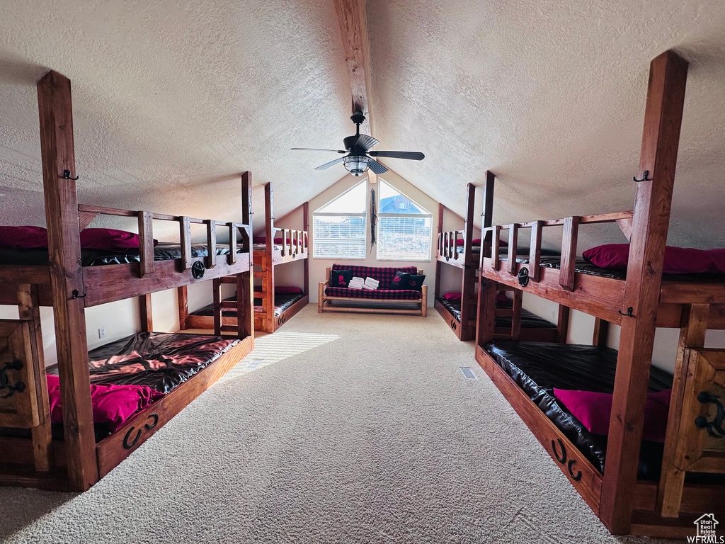 Bedroom with lofted ceiling, a textured ceiling, ceiling fan, and light colored carpet
