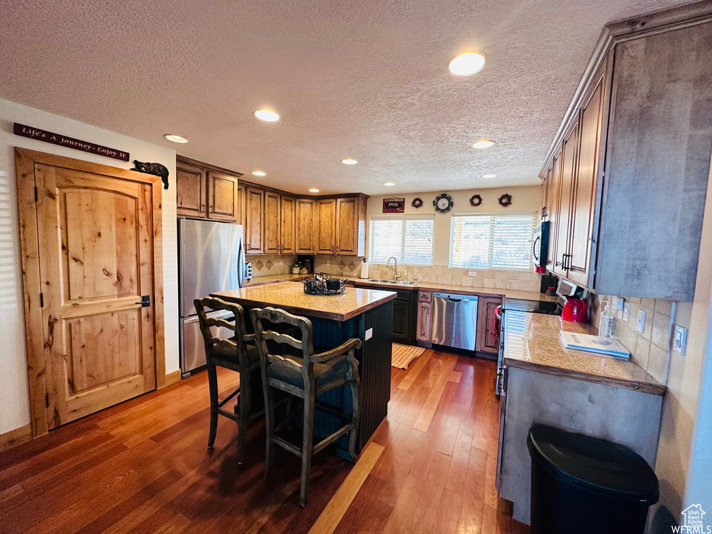 Kitchen featuring stainless steel appliances, a kitchen island, dark hardwood / wood-style floors, and sink