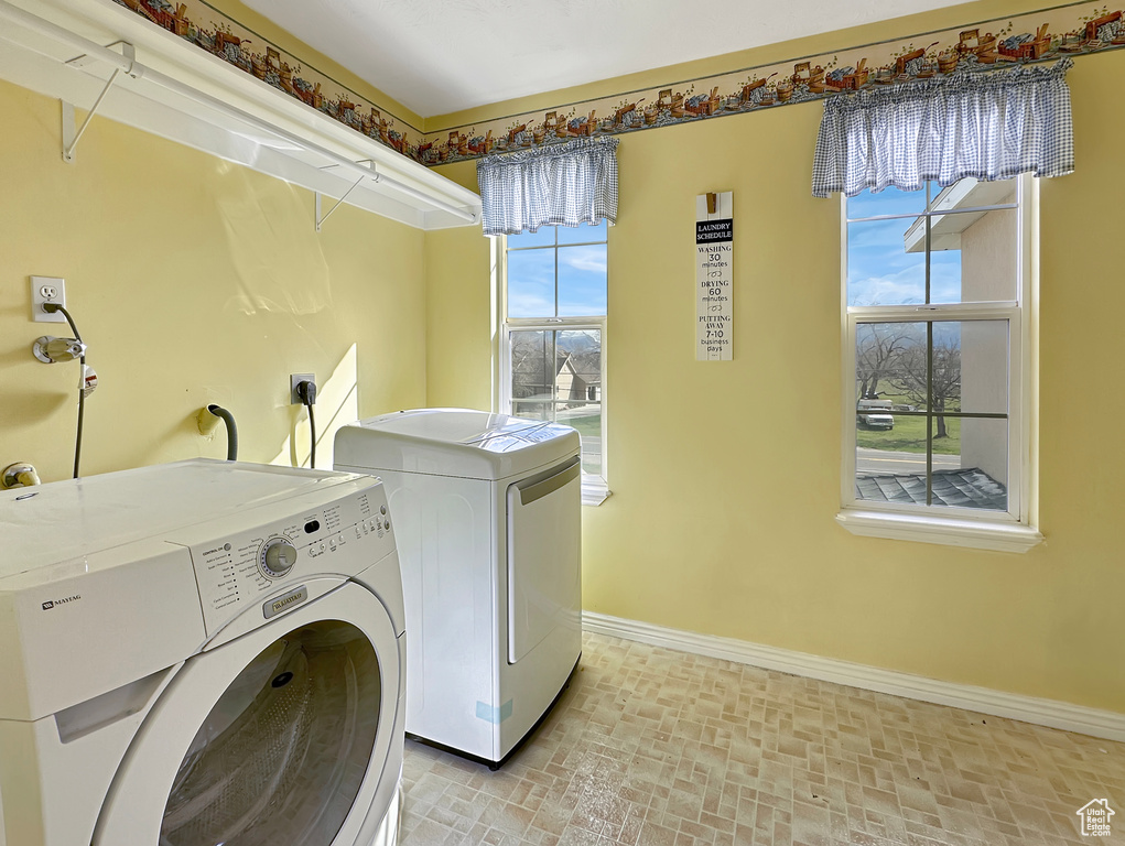 Clothes washing area featuring washing machine and dryer, electric dryer hookup, and a healthy amount of sunlight