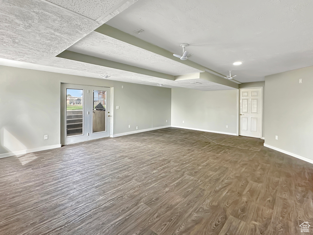 Empty room featuring a tray ceiling, french doors, and dark wood-type flooring