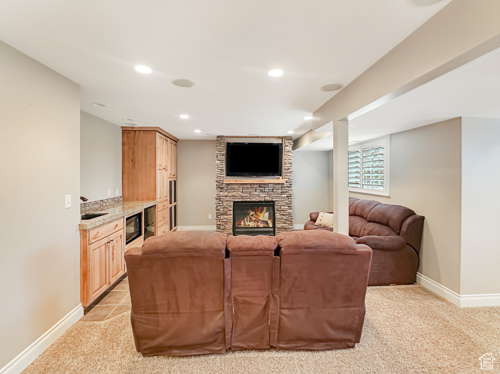 Living room featuring light tile flooring, a stone fireplace, and sink