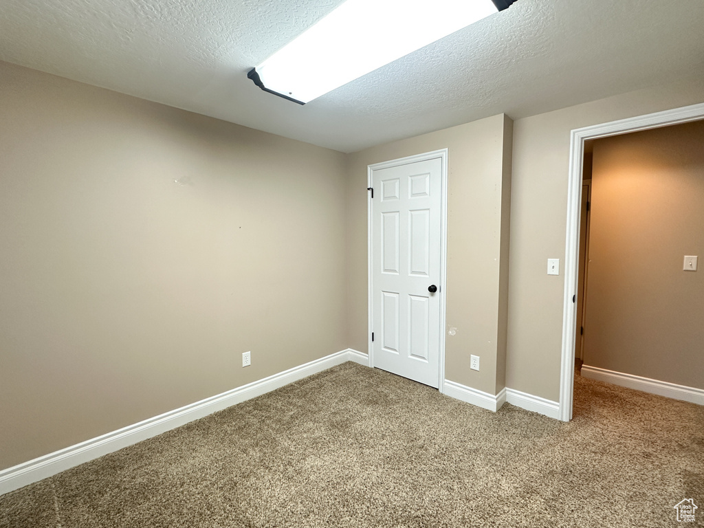 Unfurnished bedroom featuring a textured ceiling and light colored carpet