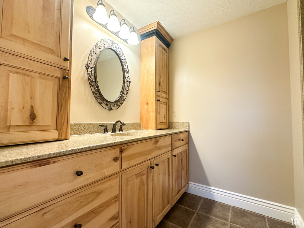 Bathroom featuring a textured ceiling, tile flooring, and vanity