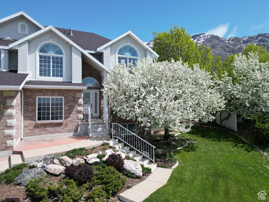 View of front of property with a mountain view and a front lawn