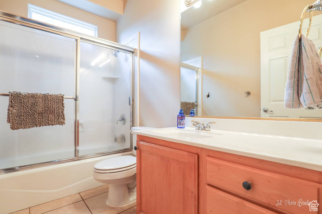 Full bathroom with toilet, combined bath / shower with glass door, large vanity, and tile flooring