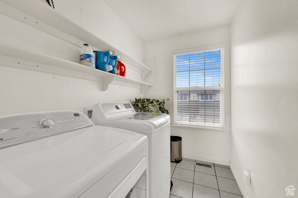 Clothes washing area with light tile floors and independent washer and dryer