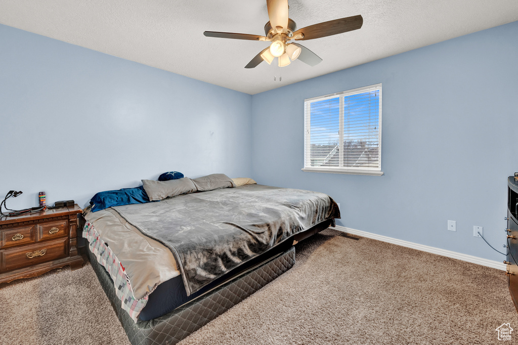 Bedroom with dark colored carpet and ceiling fan