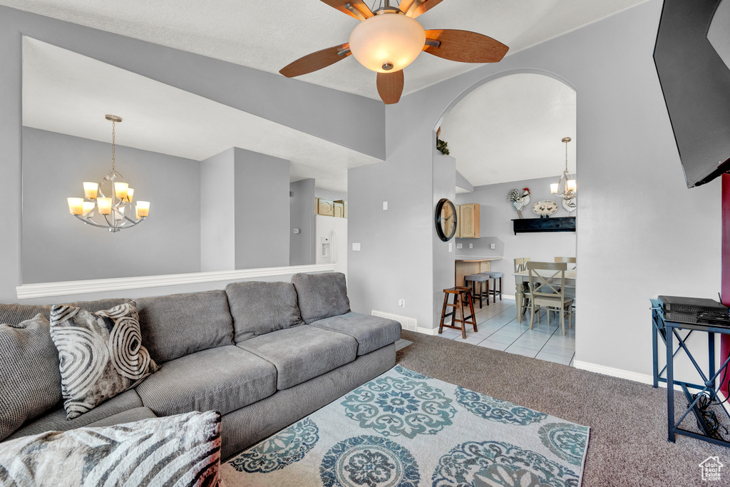 Carpeted living room featuring ceiling fan with notable chandelier