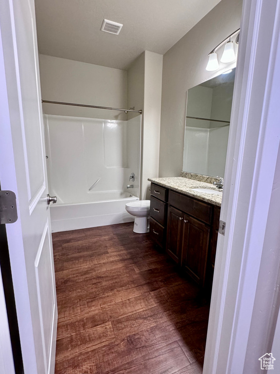 Full bathroom featuring wood-type flooring, shower / bathtub combination, vanity, and toilet