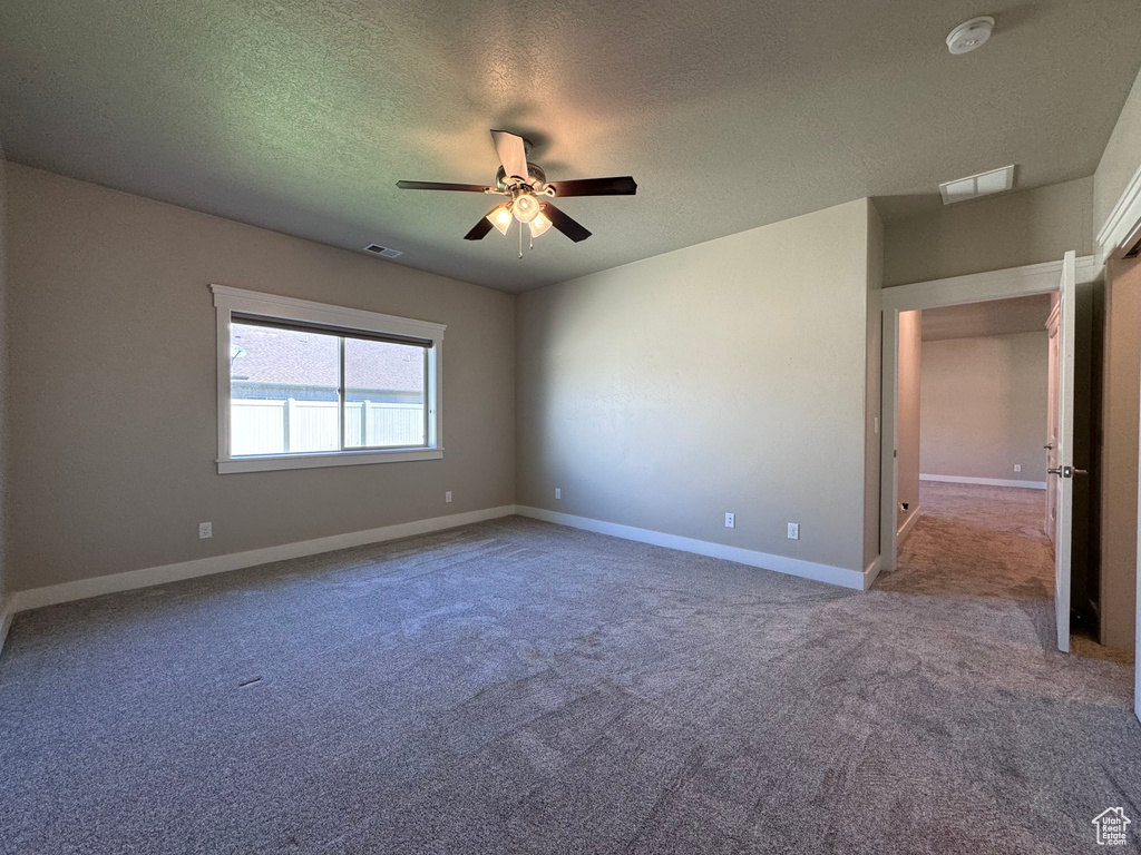 Spare room with a textured ceiling, ceiling fan, and carpet floors