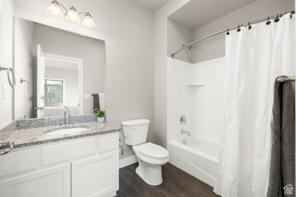 Full bathroom with shower / tub combo, vanity, hardwood / wood-style floors, and toilet