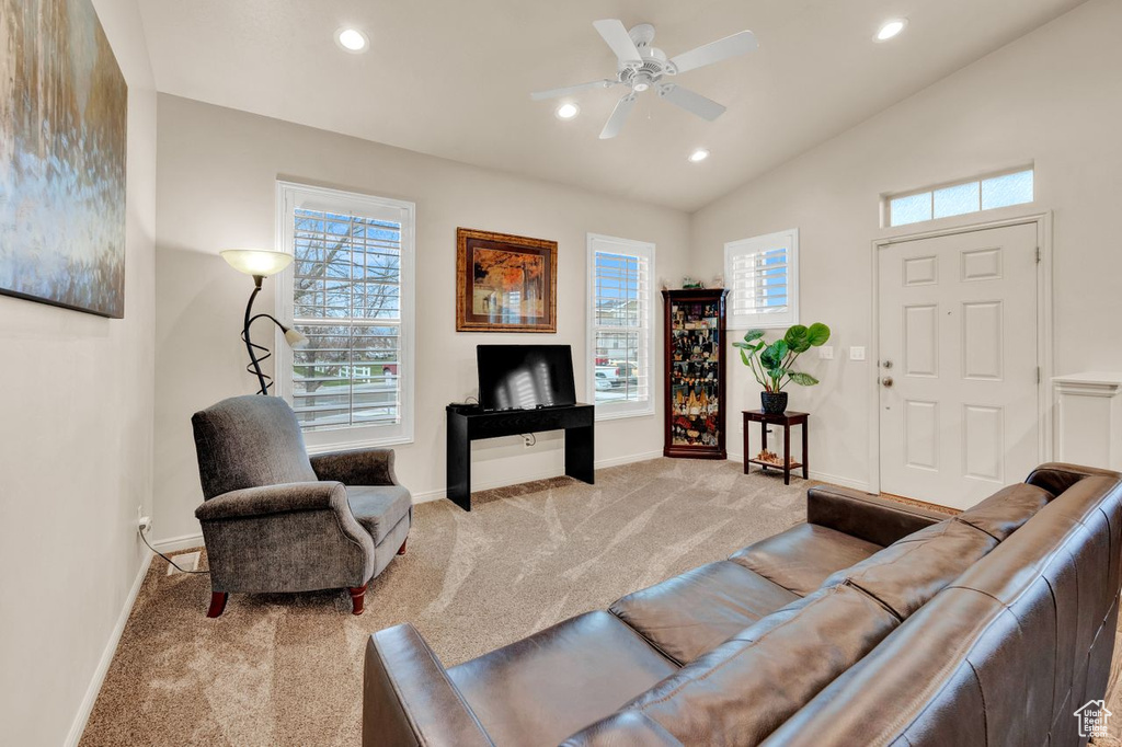Living room featuring light carpet, ceiling fan, and vaulted ceiling