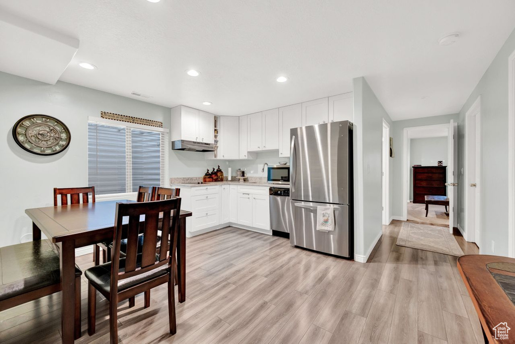 Kitchen with stainless steel appliances, white cabinets, and light hardwood / wood-style flooring