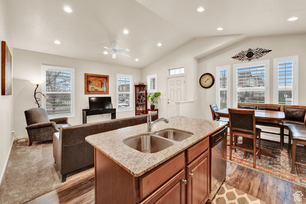 Kitchen with ceiling fan, a kitchen island with sink, sink, stainless steel dishwasher, and vaulted ceiling