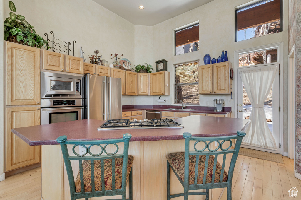 Kitchen featuring a kitchen breakfast bar, a kitchen island, sink, light hardwood / wood-style flooring, and stainless steel appliances