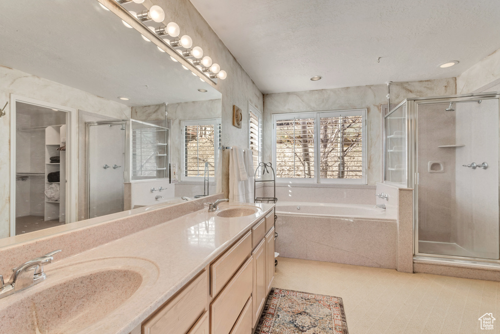 Bathroom with shower with separate bathtub, vanity with extensive cabinet space, tile floors, and dual sinks