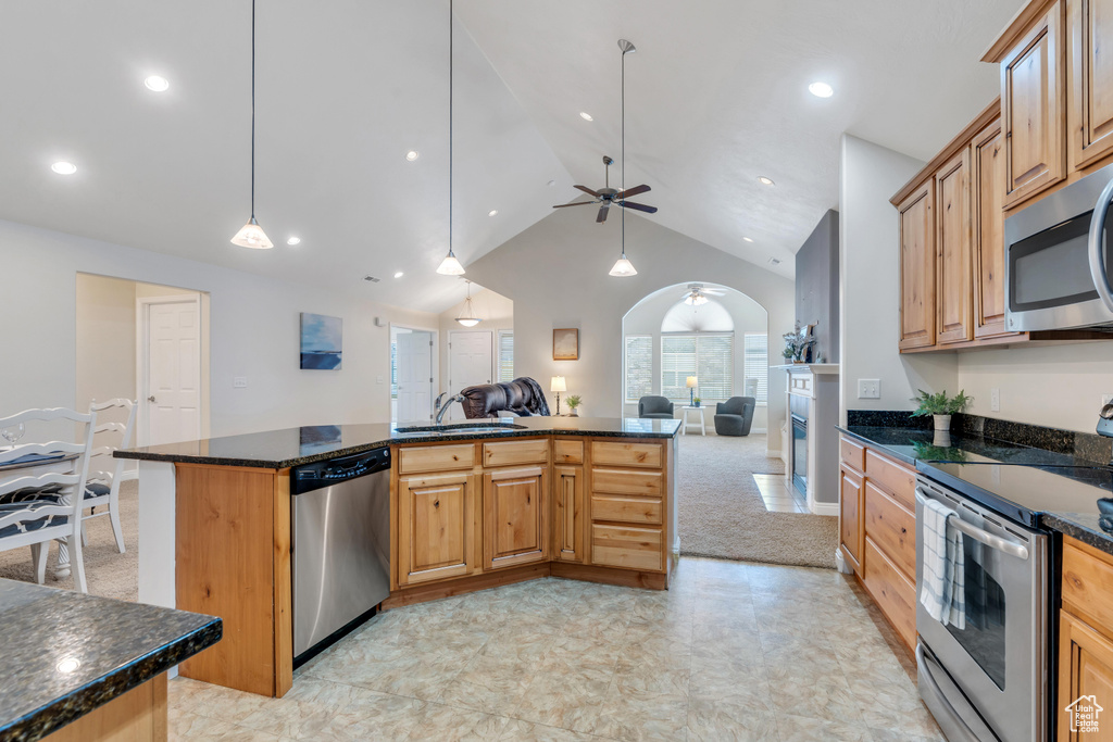 Kitchen with light tile floors, dark stone counters, ceiling fan, appliances with stainless steel finishes, and sink