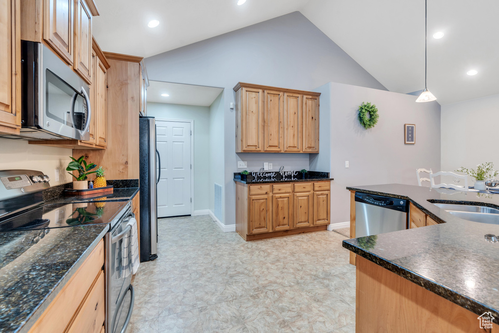 Kitchen featuring decorative light fixtures, appliances with stainless steel finishes, high vaulted ceiling, sink, and light tile floors