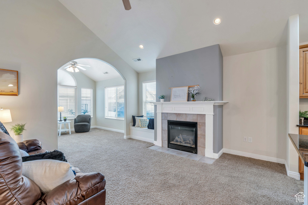 Living room featuring light colored carpet, ceiling fan, a tile fireplace, and lofted ceiling
