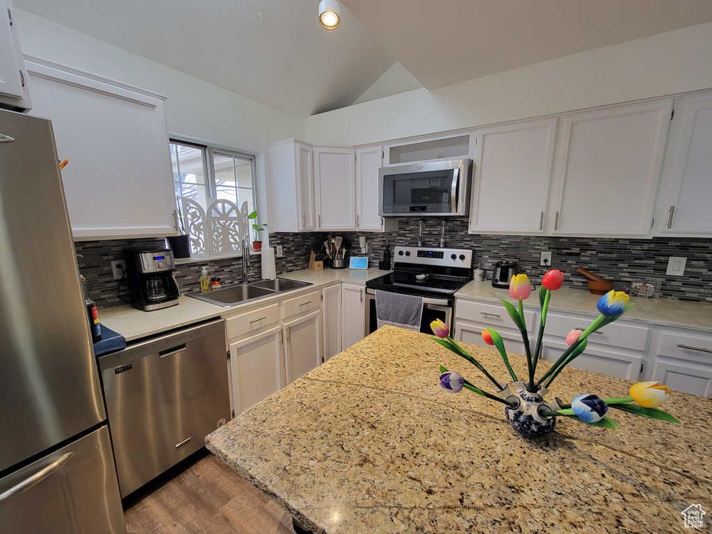 Kitchen with backsplash, white cabinets, and appliances with stainless steel finishes