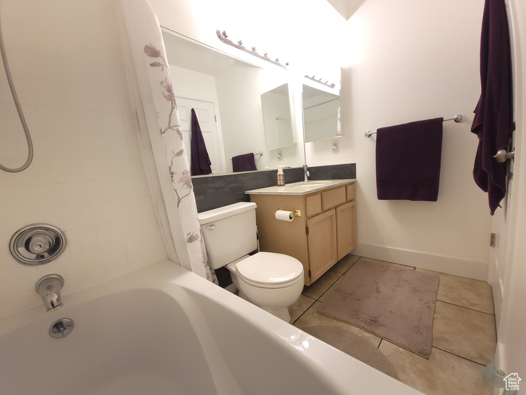 Full bathroom featuring toilet, tile floors, shower / tub combo with curtain, and vanity