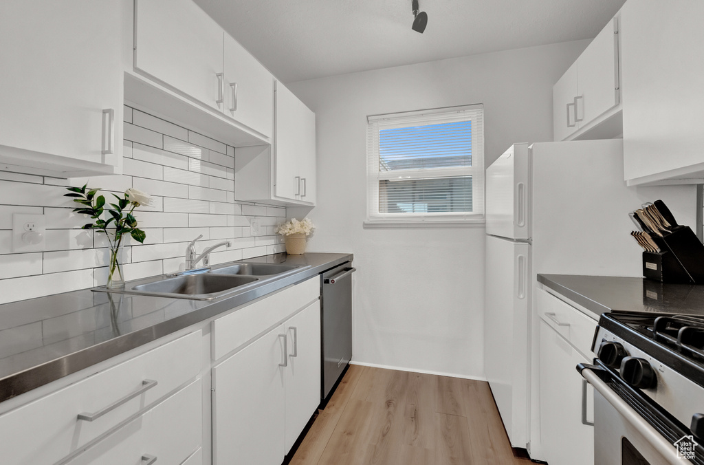 Kitchen featuring light hardwood / wood-style floors, stainless steel appliances, white cabinets, backsplash, and sink