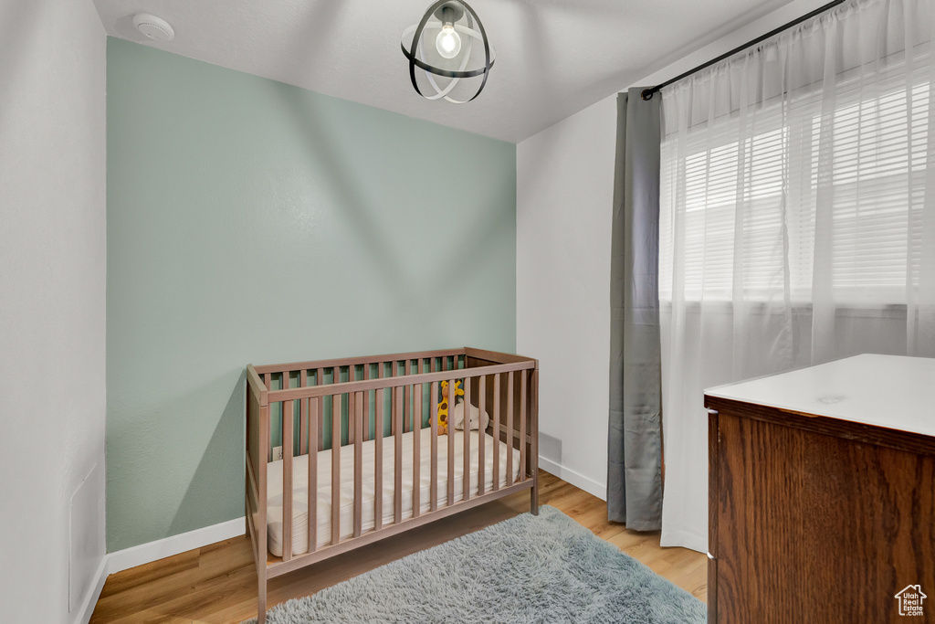 Bedroom with a nursery area and light hardwood / wood-style floors