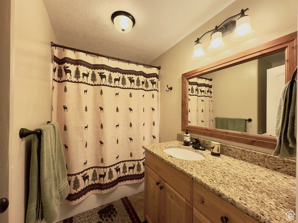Bathroom featuring a textured ceiling, tile flooring, and oversized vanity