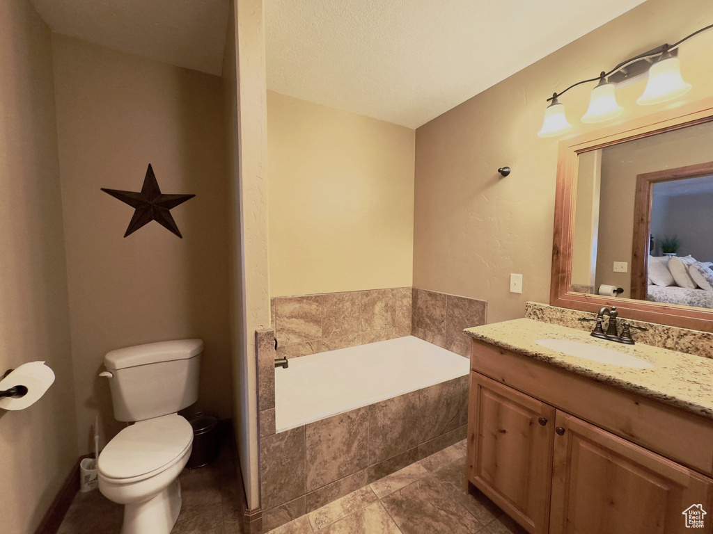 Bathroom featuring toilet, tile floors, a bath, and vanity