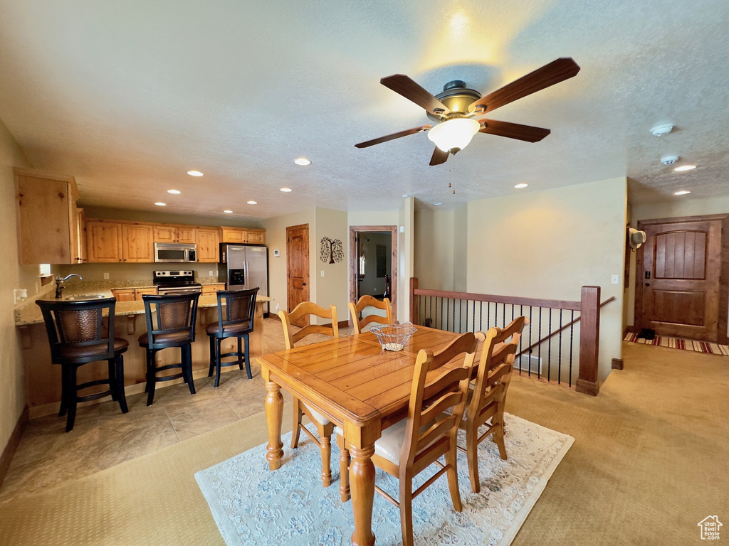 Dining room featuring ceiling fan, sink, and light colored carpet